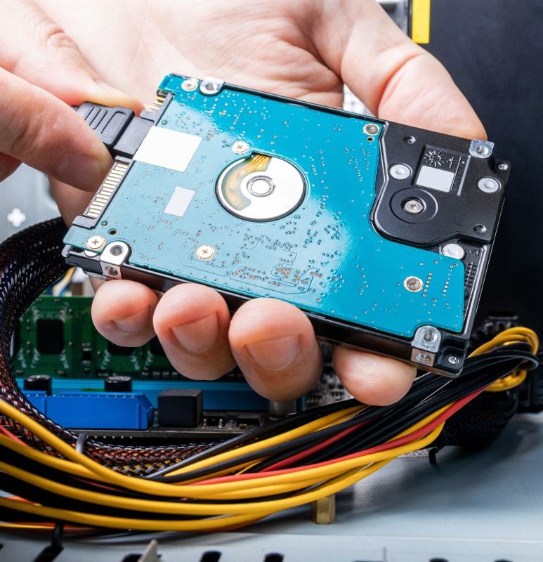 A technician disconnecting a hard drive from a computer to safely recover and transfer data at New Ross PC Repairs.