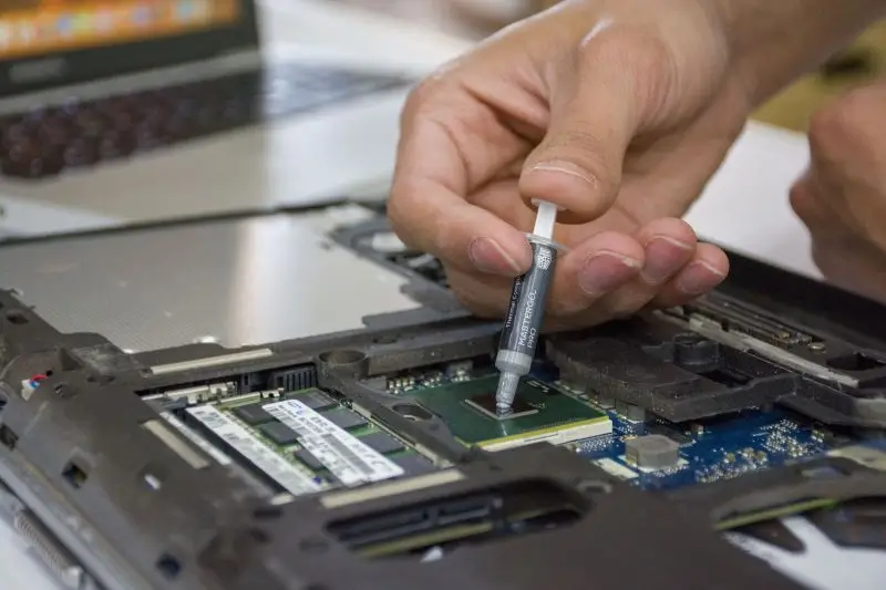 Technician applying fresh thermal paste to a laptop processor during a hardware repair at New Ross PC Repairs.